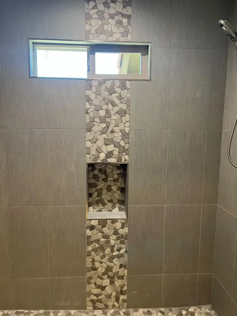 Modern tiled shower with pebble stone accent